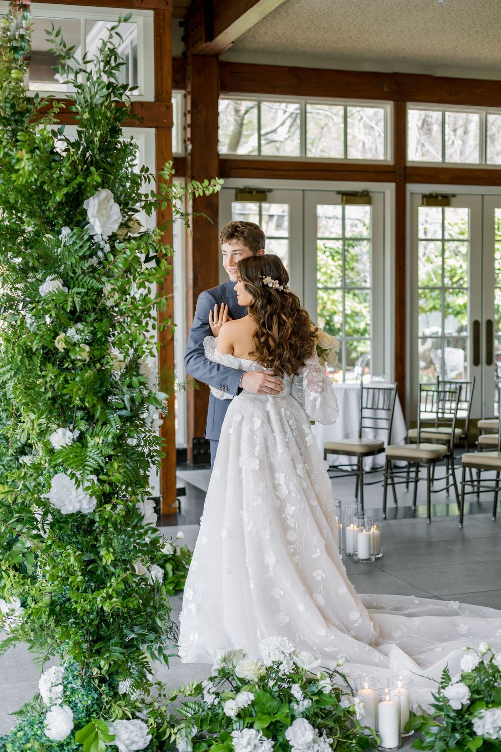 A couple shares a romantic dance surrounded by elegant white floral arrangements and candlelight.