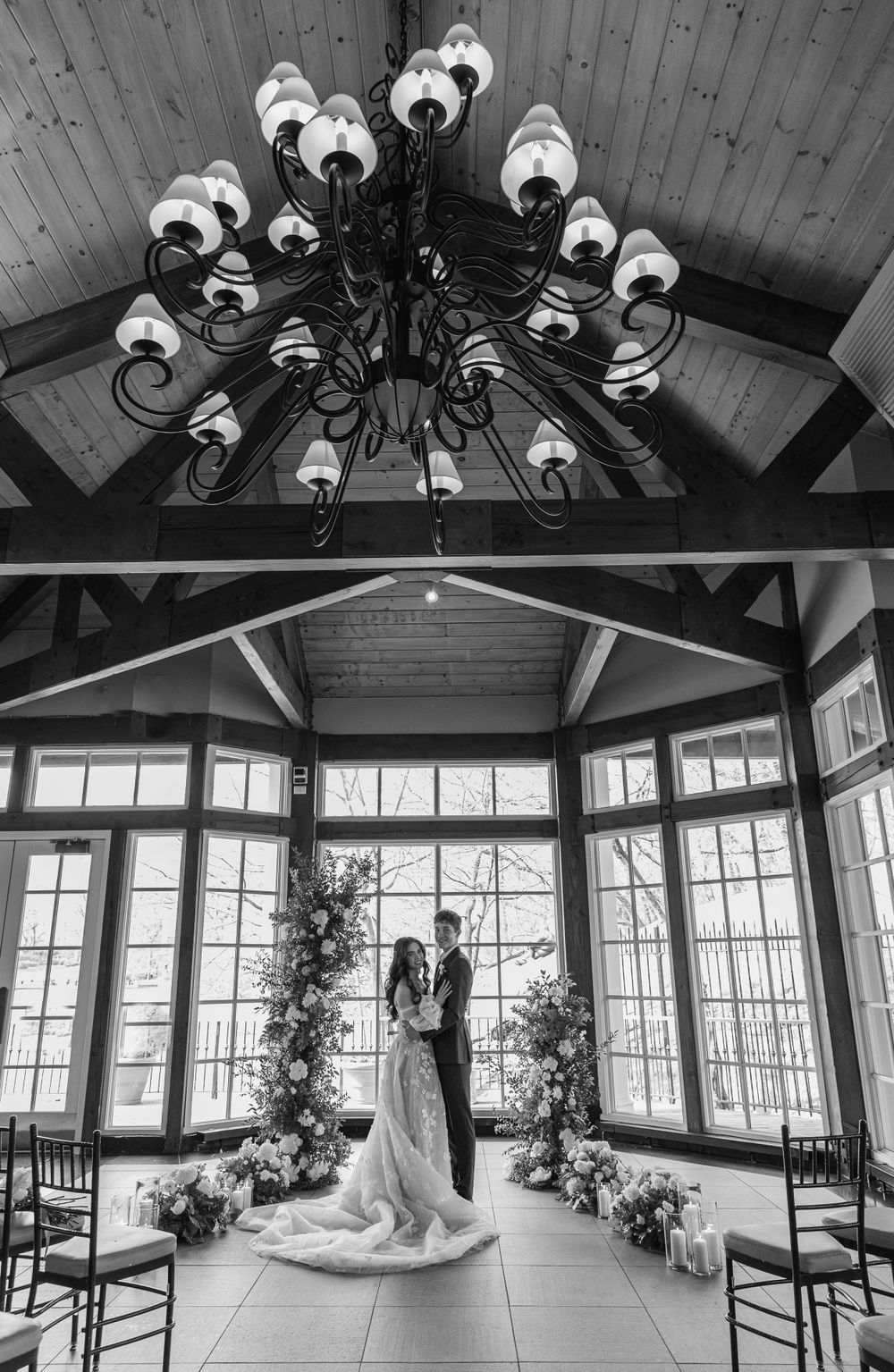 Dramatic black and white wedding ceremony venue with chandelier and floral arch decorations.
