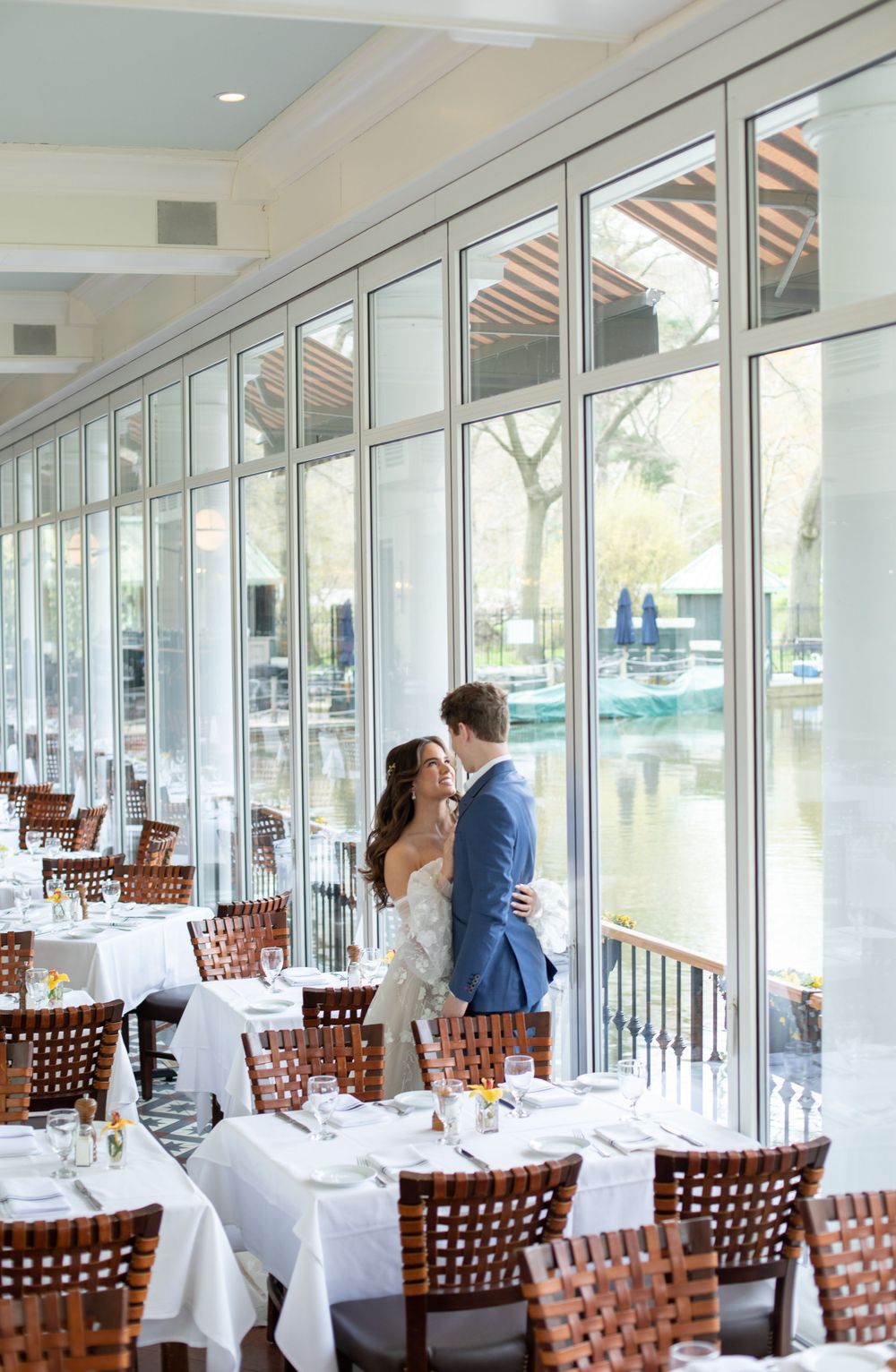 Wedding couple silhouetted against bright windows in an elegant waterfront restaurant.