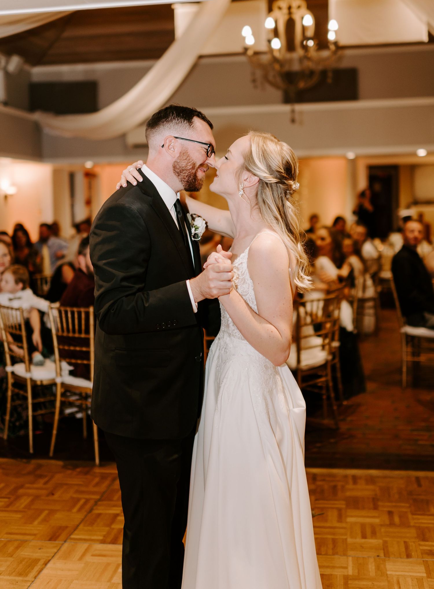 Couple shares romantic dance moment at elegant indoor wedding reception.