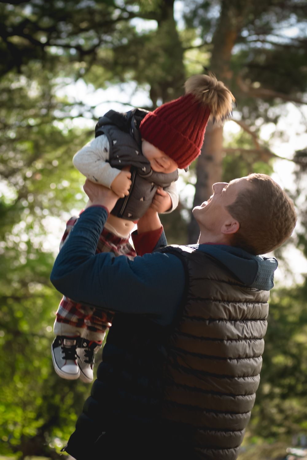 Heartwarming outdoor family moment captured in natural sunlight among trees.