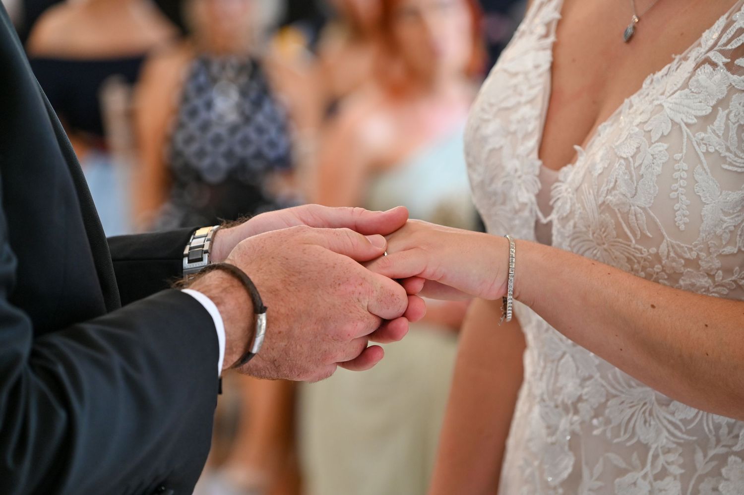 Close-up shot of hands exchanging wedding rings during ceremony.