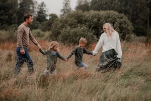 Familj hand i hand på en äng i Bålsta