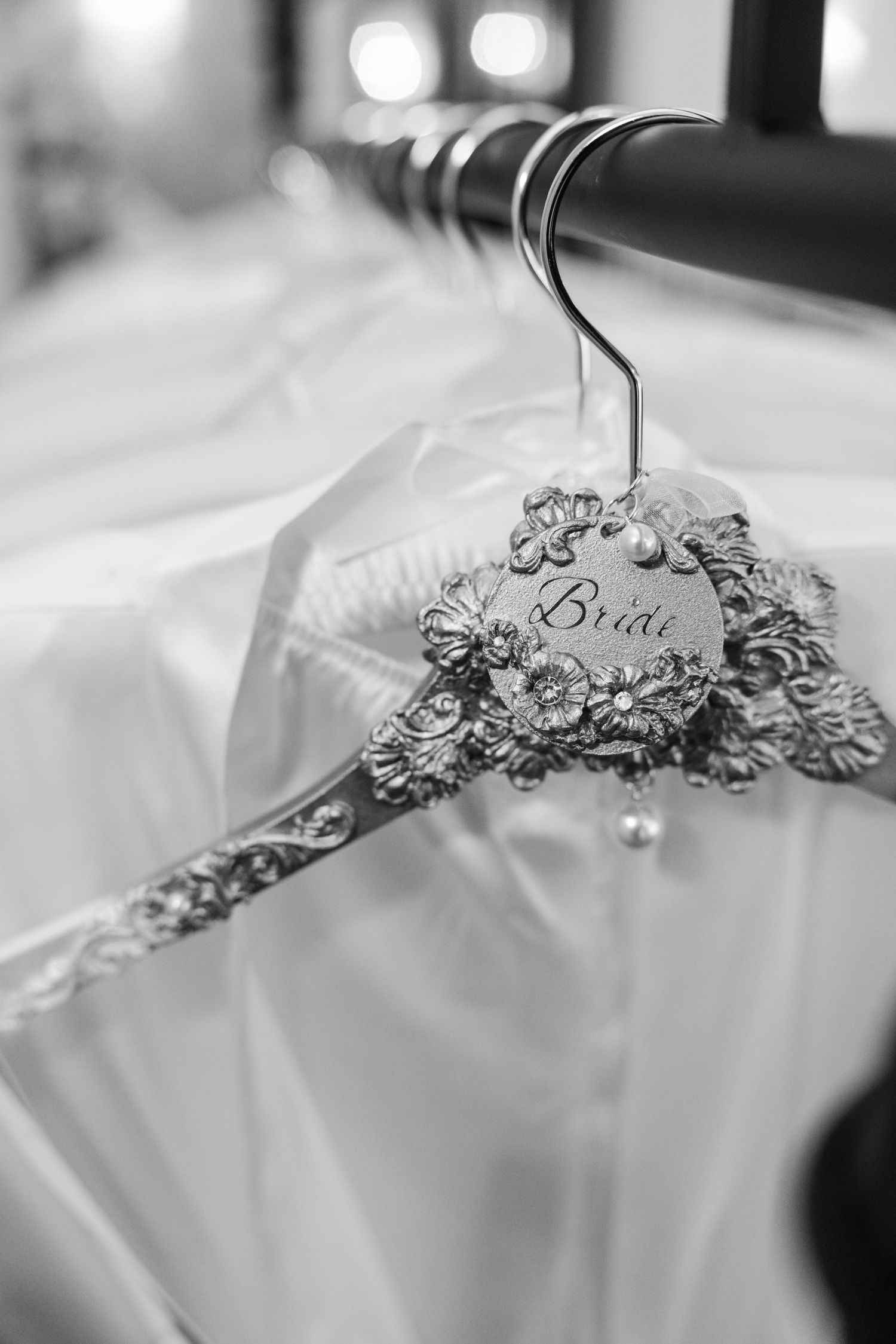 A decorative bridal hanger with ornate details holding a white wedding dress.