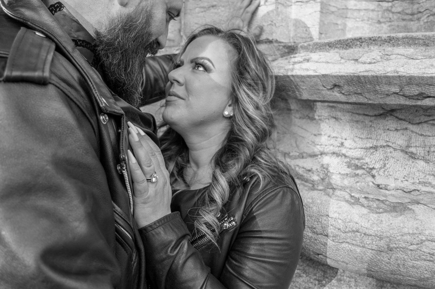 Romantic black and white portrait against stone wall backdrop.
