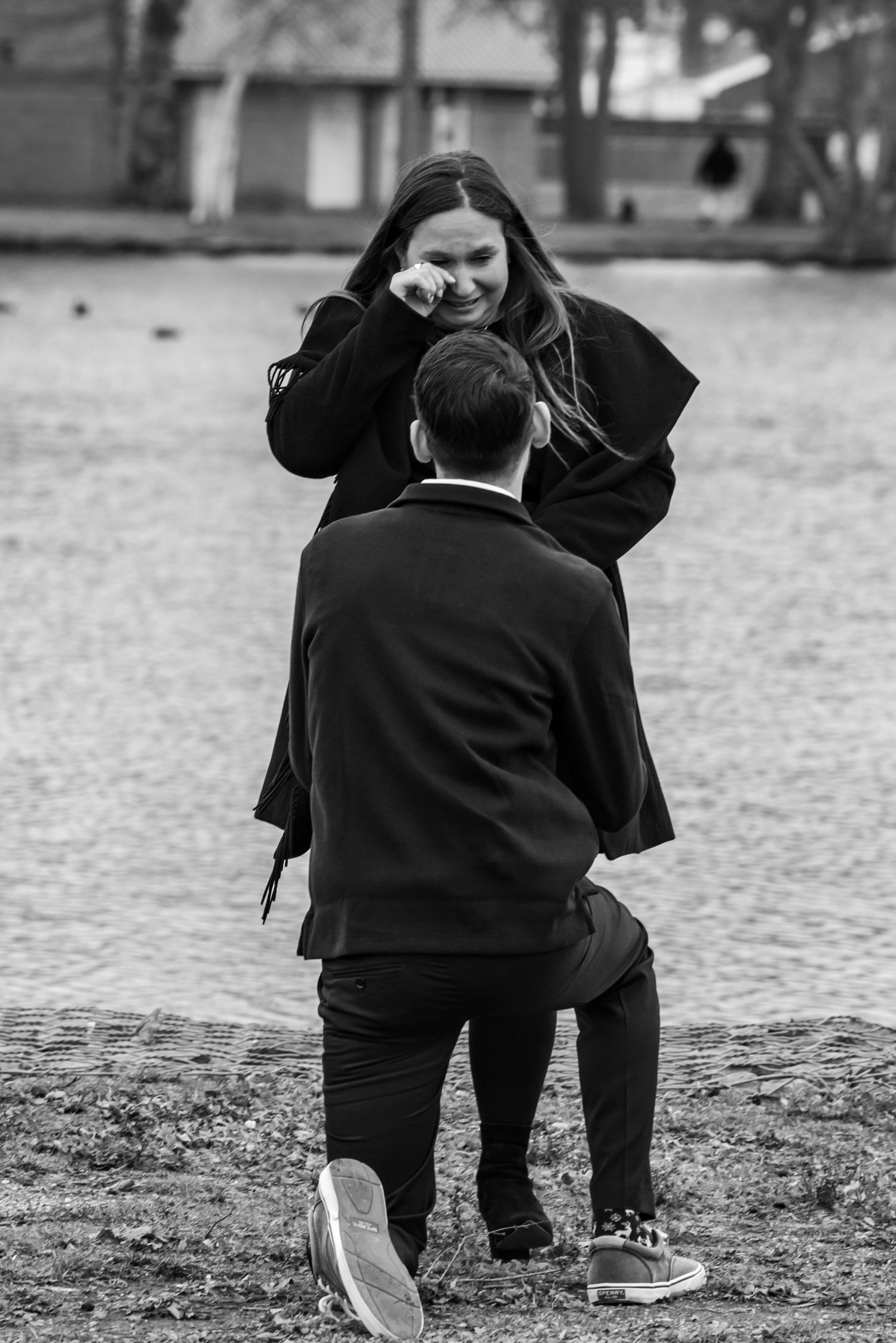 A proposal moment captured in black and white as someone kneels on a rock outdoors.