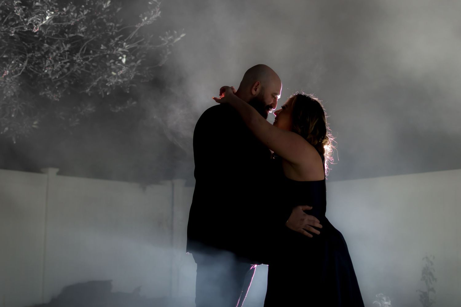 Atmospheric engagement photo with couple embracing in misty setting.