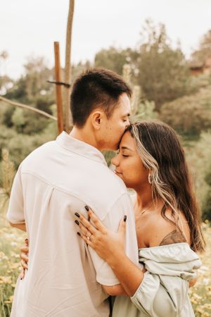 A tender moment between a couple embracing in a sunlit wildflower field.