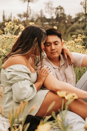 A romantic couple shares an intimate moment together in a field of yellow wildflowers at sunset.