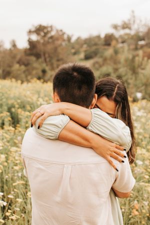 A romantic embrace captured in a field of wildflowers during golden hour.