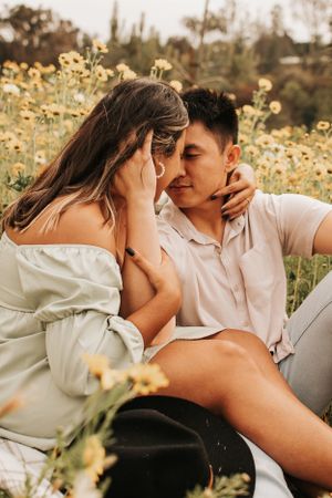 An intimate moment between a couple sitting among blooming yellow wildflowers.
