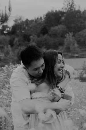 A joyful black and white portrait of a couple laughing and embracing outdoors.
