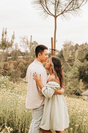 A romantic embrace between a couple standing among desert plants and wildflowers.