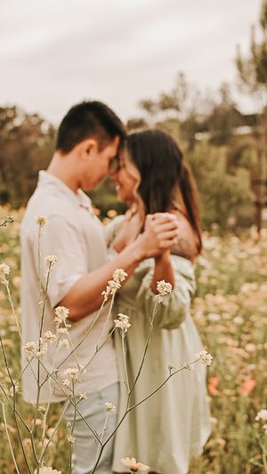 Romantic couple embracing in wildflower field during golden hour.