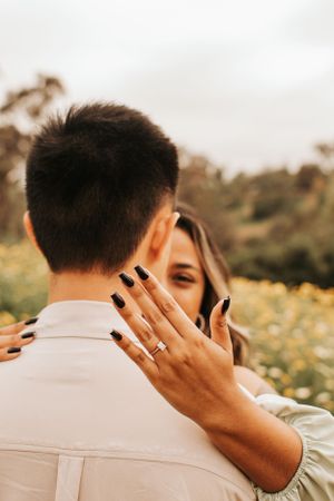 A couple shares an intimate moment in a flower field as she shows off her ring.