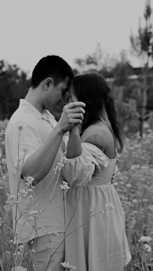 Black and white photo of couple dancing among wildflowers at dusk.