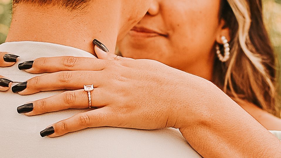 Close-up of engagement ring on woman's hand with black nail polish.