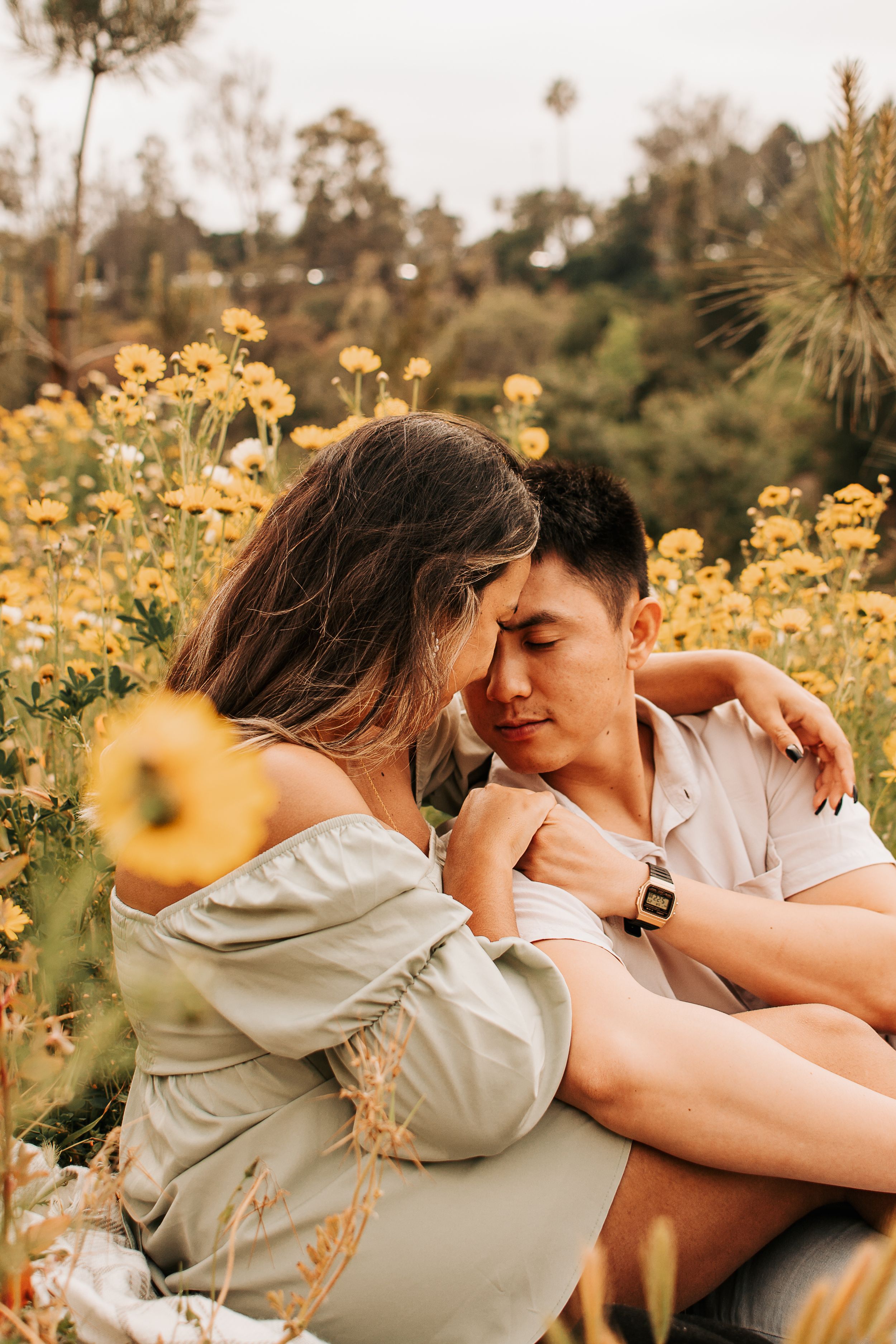 Intimate couple moment captured among blooming yellow wildflowers at sunset.