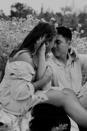 A black and white portrait of a couple sharing a tender moment in a flower field.