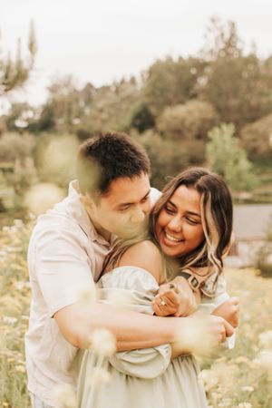 A tender moment between a couple sharing laughter in a sunlit meadow.