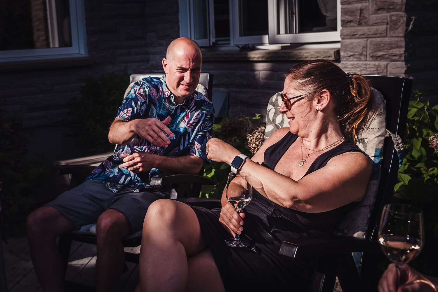 Colour image of two adults sitting outside in deck chairs.