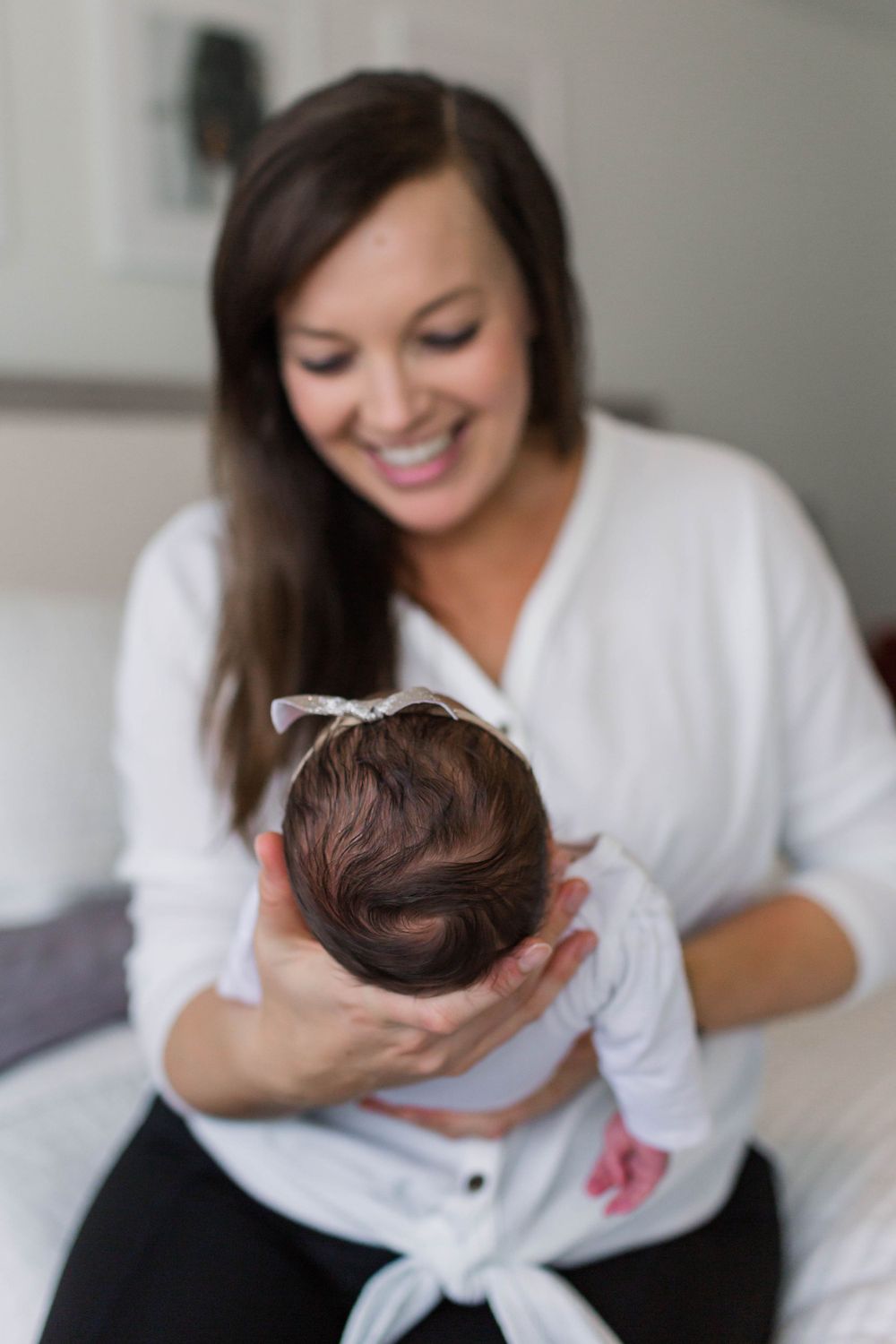 Woman in white robe holding and admiring a newborn baby during an intimate photo session.