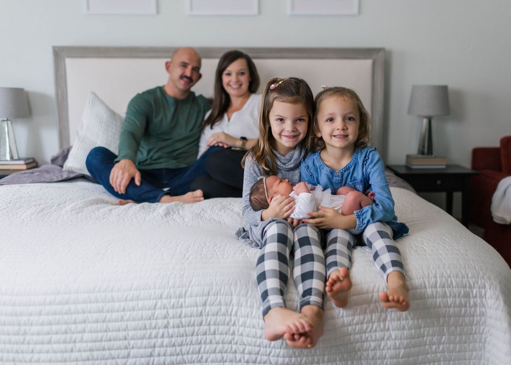 Family members lounging together on a white bed wearing matching pajamas.