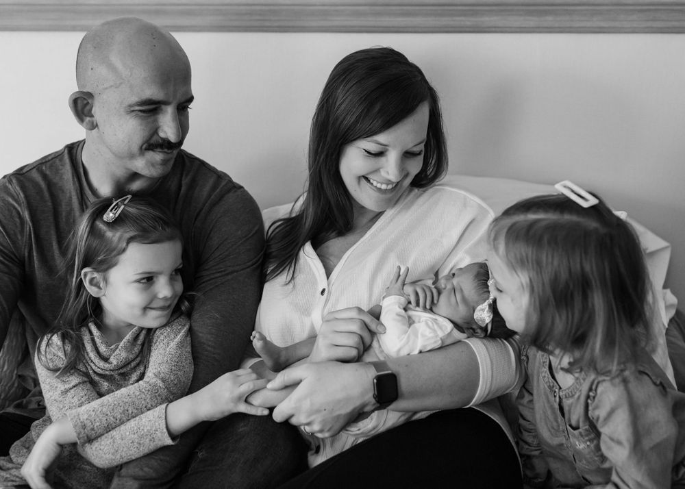 A family sharing intimate moments together on a gray backdrop in black and white photography.