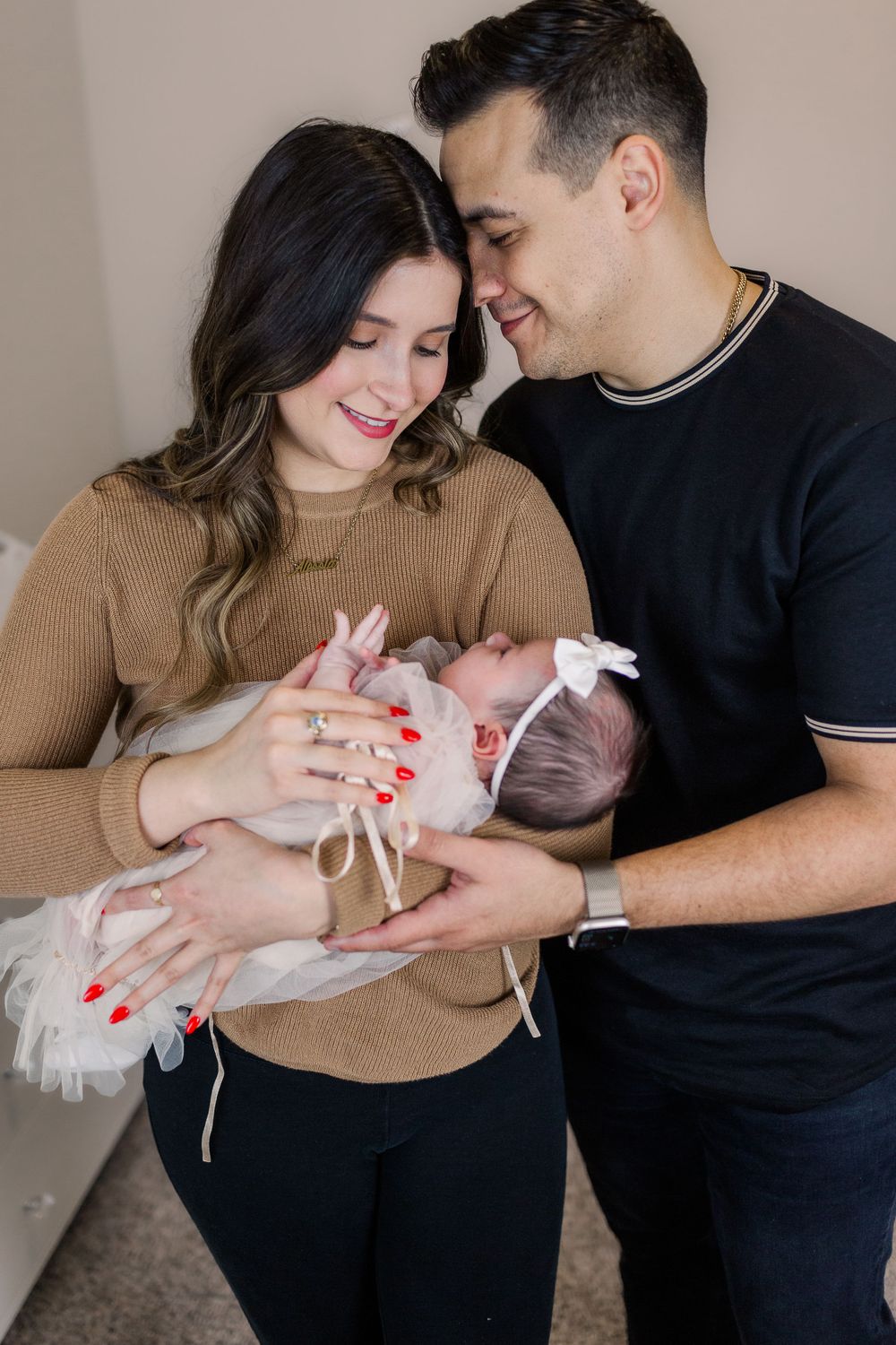 A tender family moment with parents cradling their newborn baby in a series of connected photos.