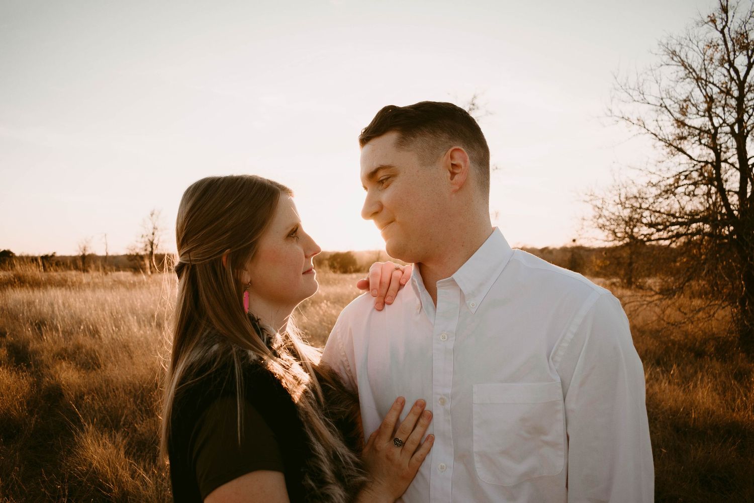 Tender moment between a couple in casual attire during a sunset photoshoot.