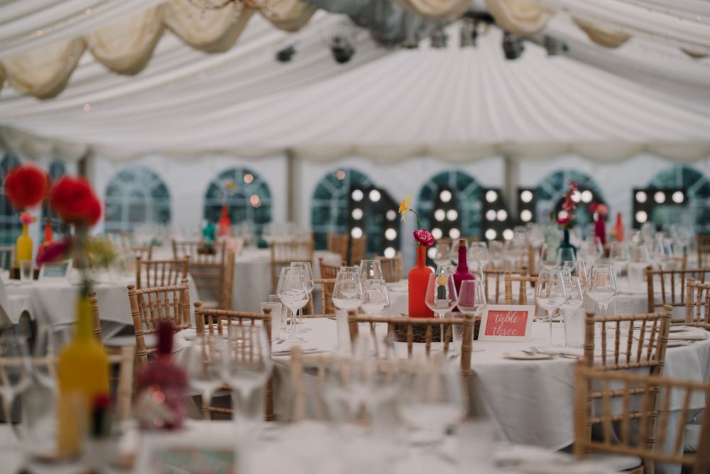 Elegant wedding reception tent setup with chiavari chairs and draped white fabric ceiling.