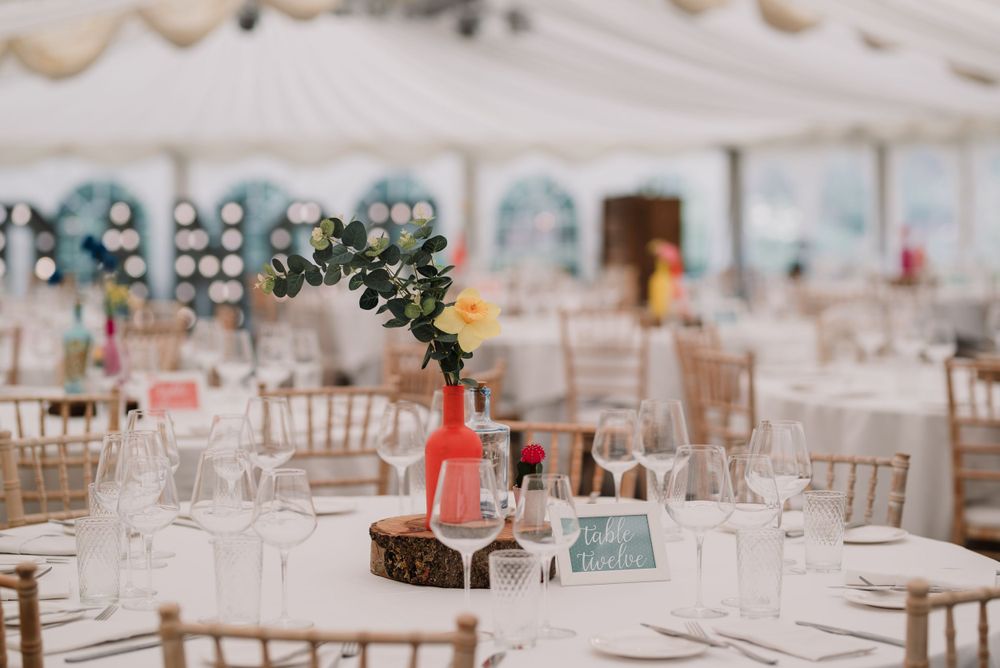 Elegant wedding reception table setting with floral centerpiece and gold chiavari chairs.
