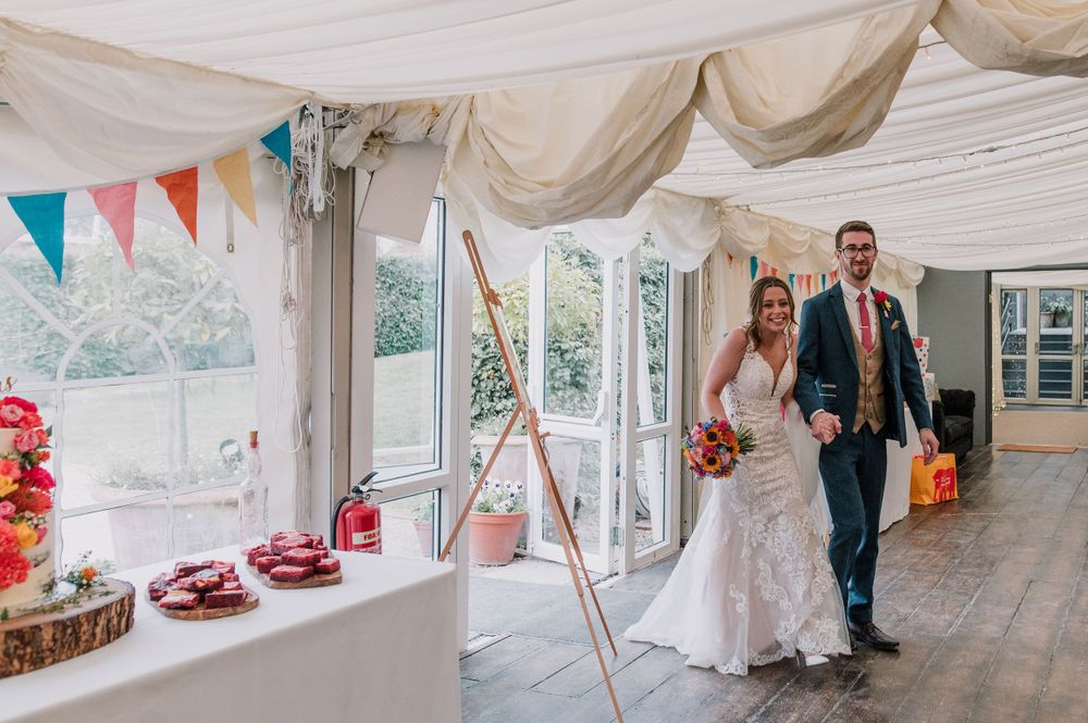 A wedding reception venue decorated with bunting and white drapes features a dessert table and celebration space.