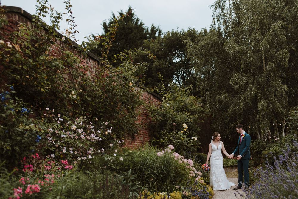 Romantic garden setting with blooming flowers and brick wall backdrop.