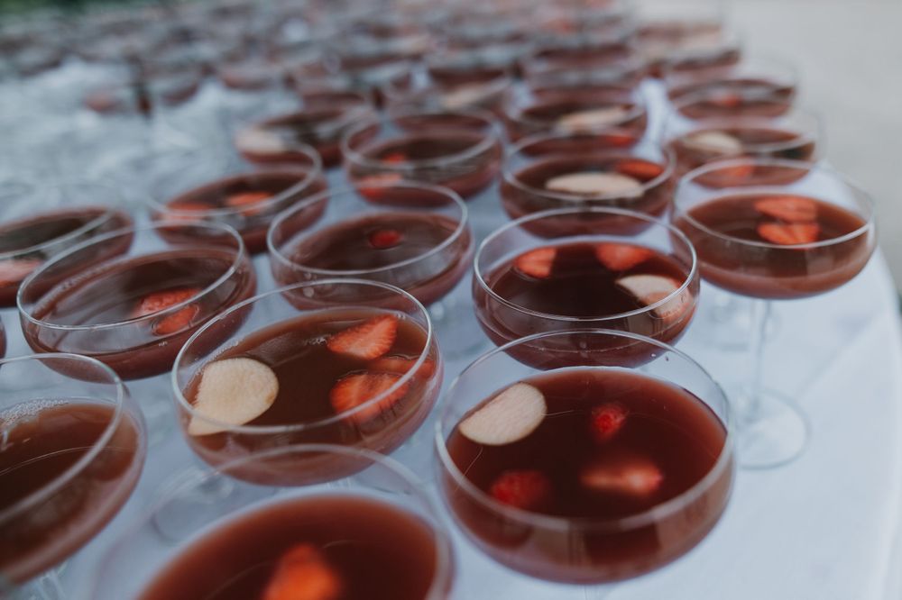 Rows of glass cups filled with red cocktails arranged on serving tray.