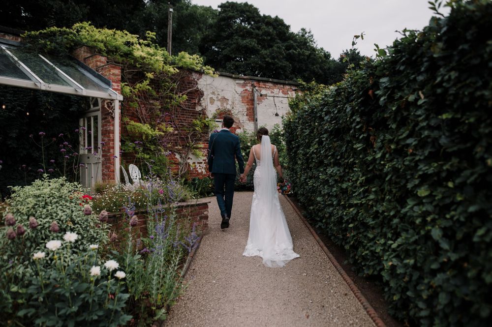 Garden pathway with brick walls and lush greenery at wedding venue.