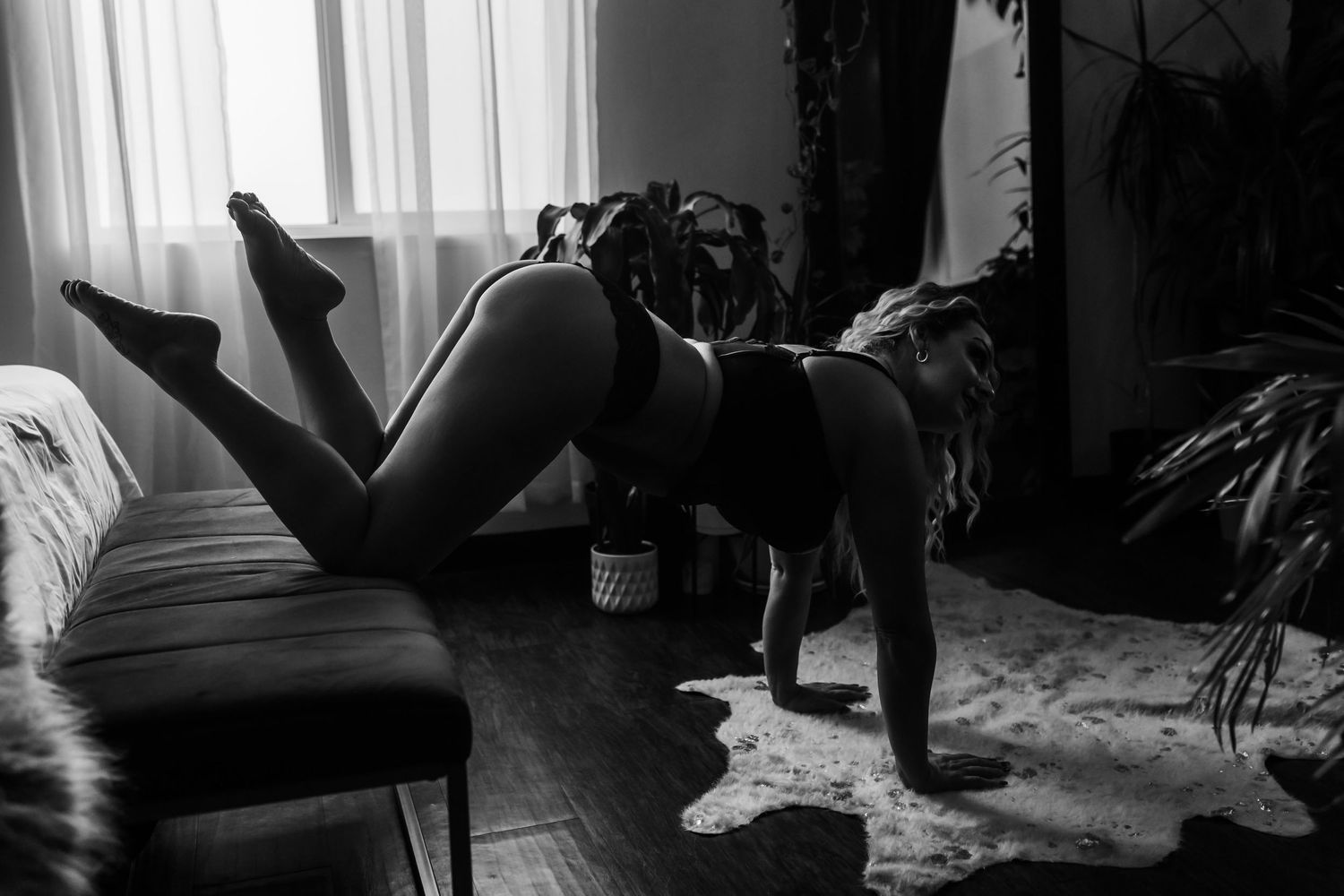 Black and white photo of person relaxing on couch with dog in moody interior setting.
