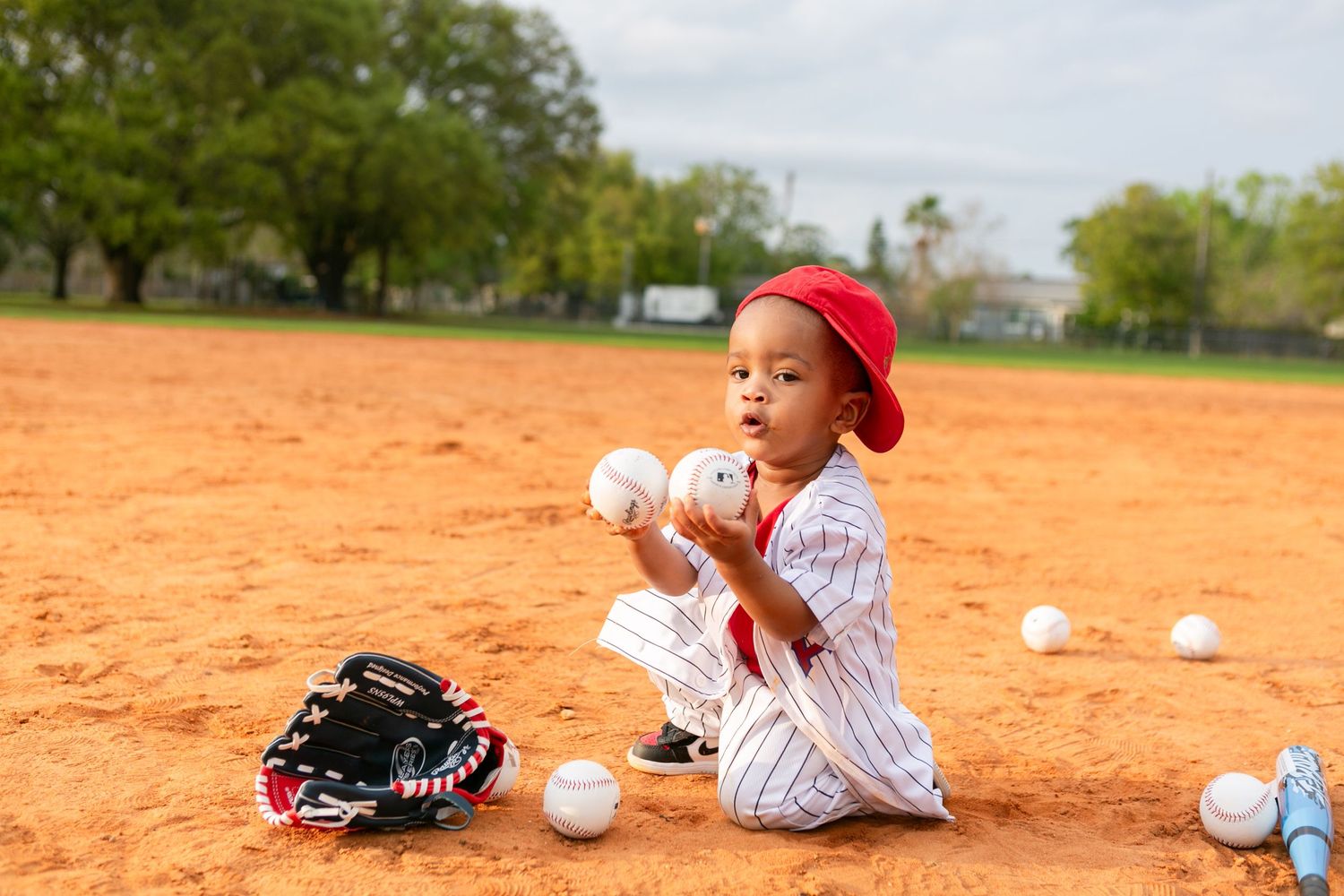 Sanford FL Cake Smash Photography boy holding baseballs on the baseball field