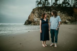 couple holds hands while looking at each other on the coast maternity photographer portland oregon