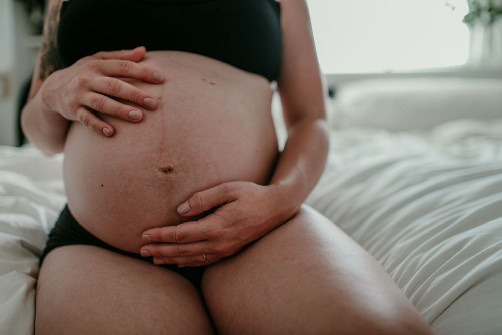 close up shot of pregnant persons hands on naked belly portland oregon documentary maternity photographer