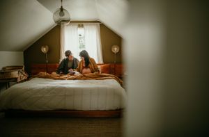 queer couple does crossword puzzle in bed maternity photography session portland oregon