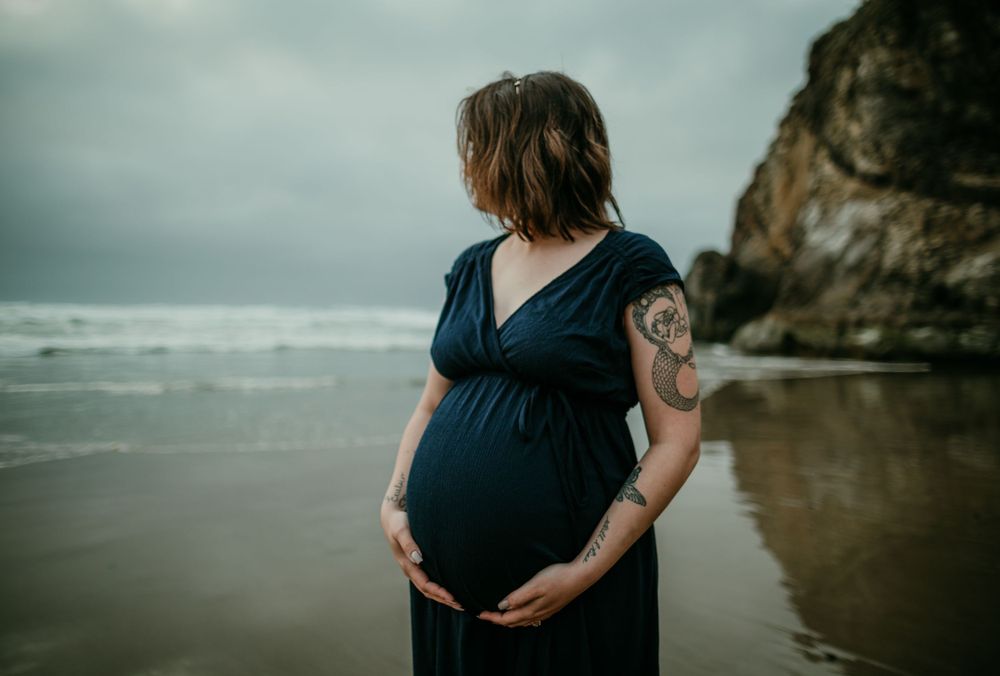image of pregnant person holding belly pregnant with twins on the oregon coast maternity photographer portland oregon