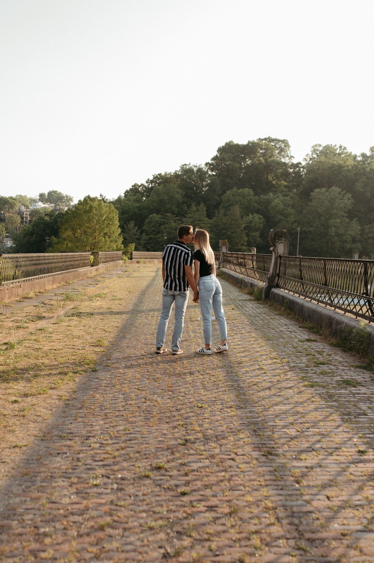 Couple walking together on a cobblestone bridge during golden hour.