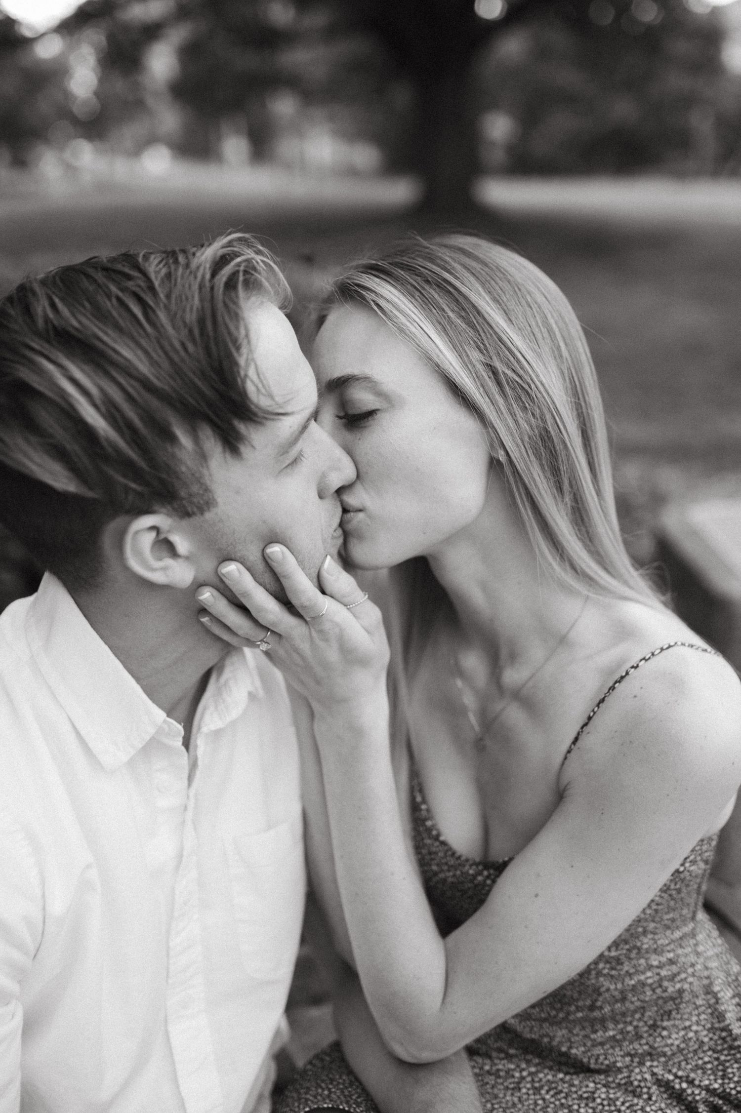 Black and white romantic portrait of couple sharing an intimate kiss outdoors.