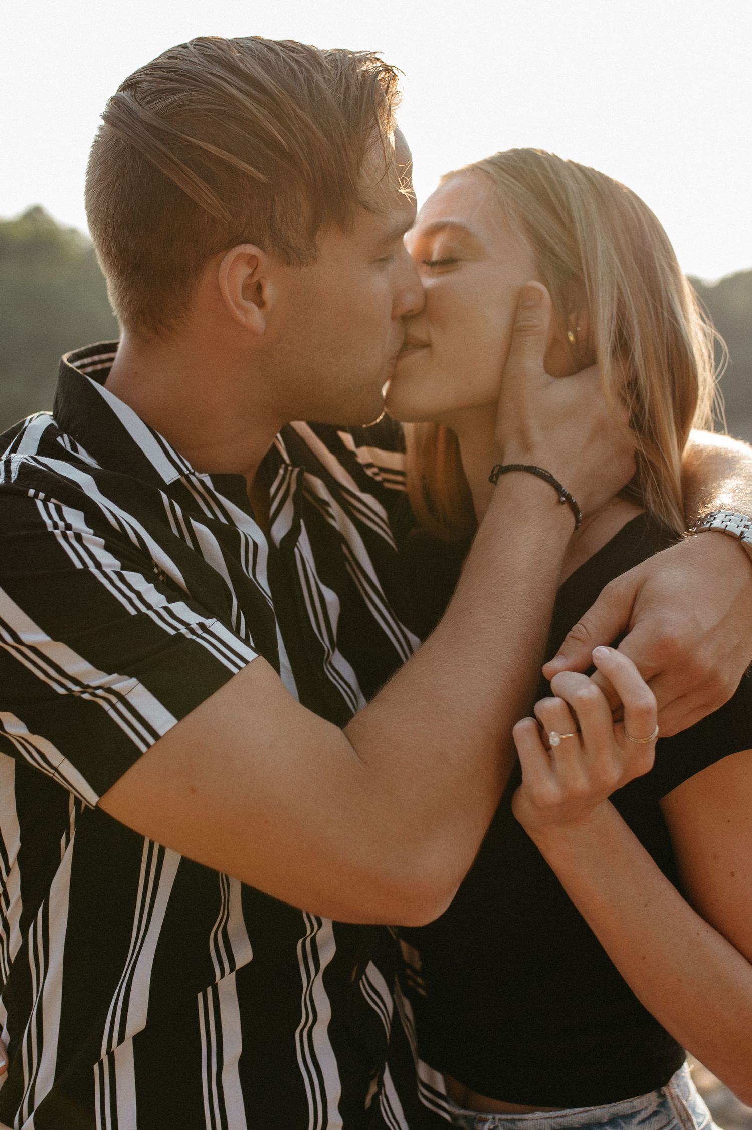 Sunset silhouette of a tender kiss between couple in casual attire.