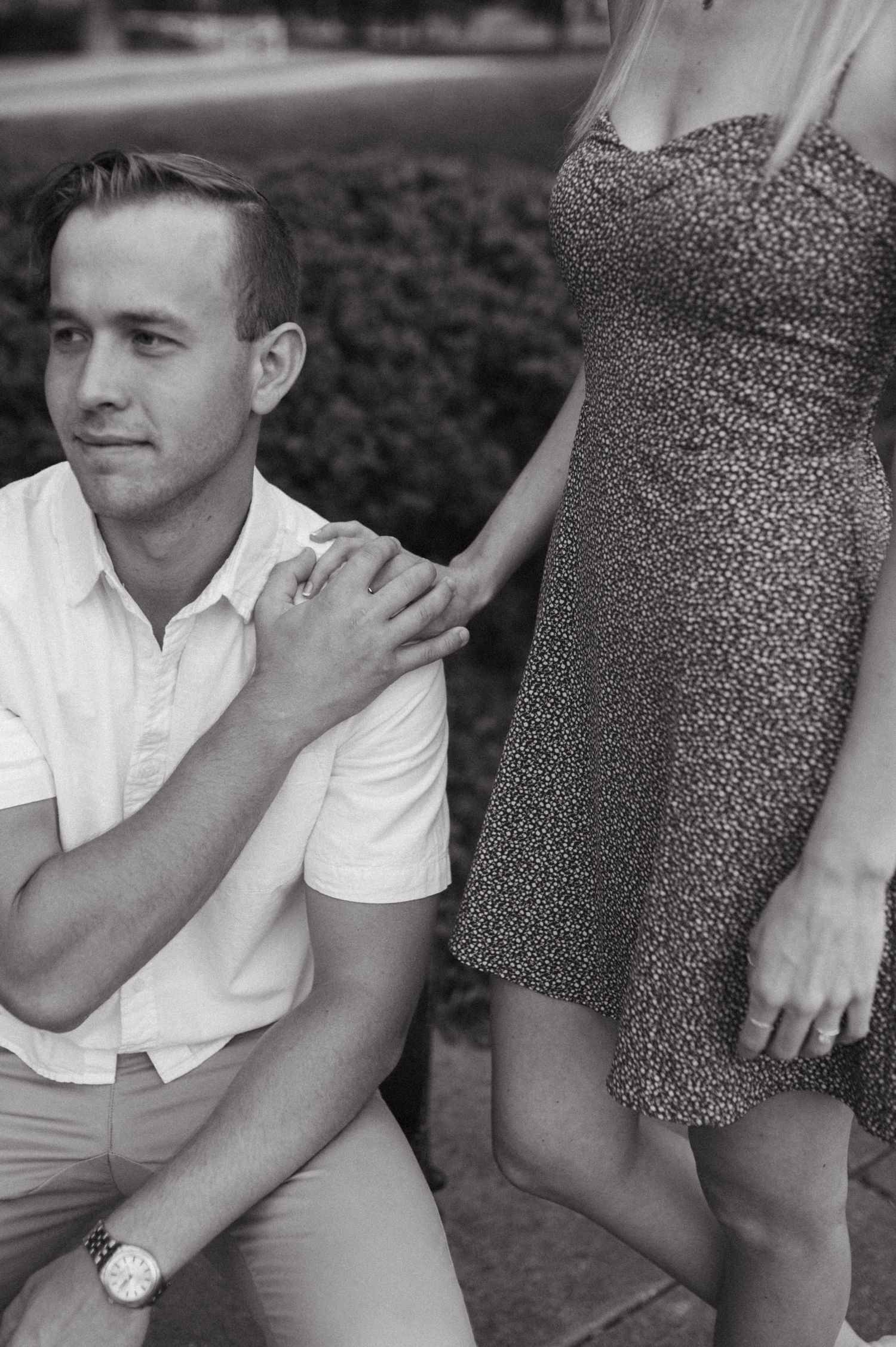 Couple poses outdoors with person in white shirt sitting next to someone in a floral summer dress.