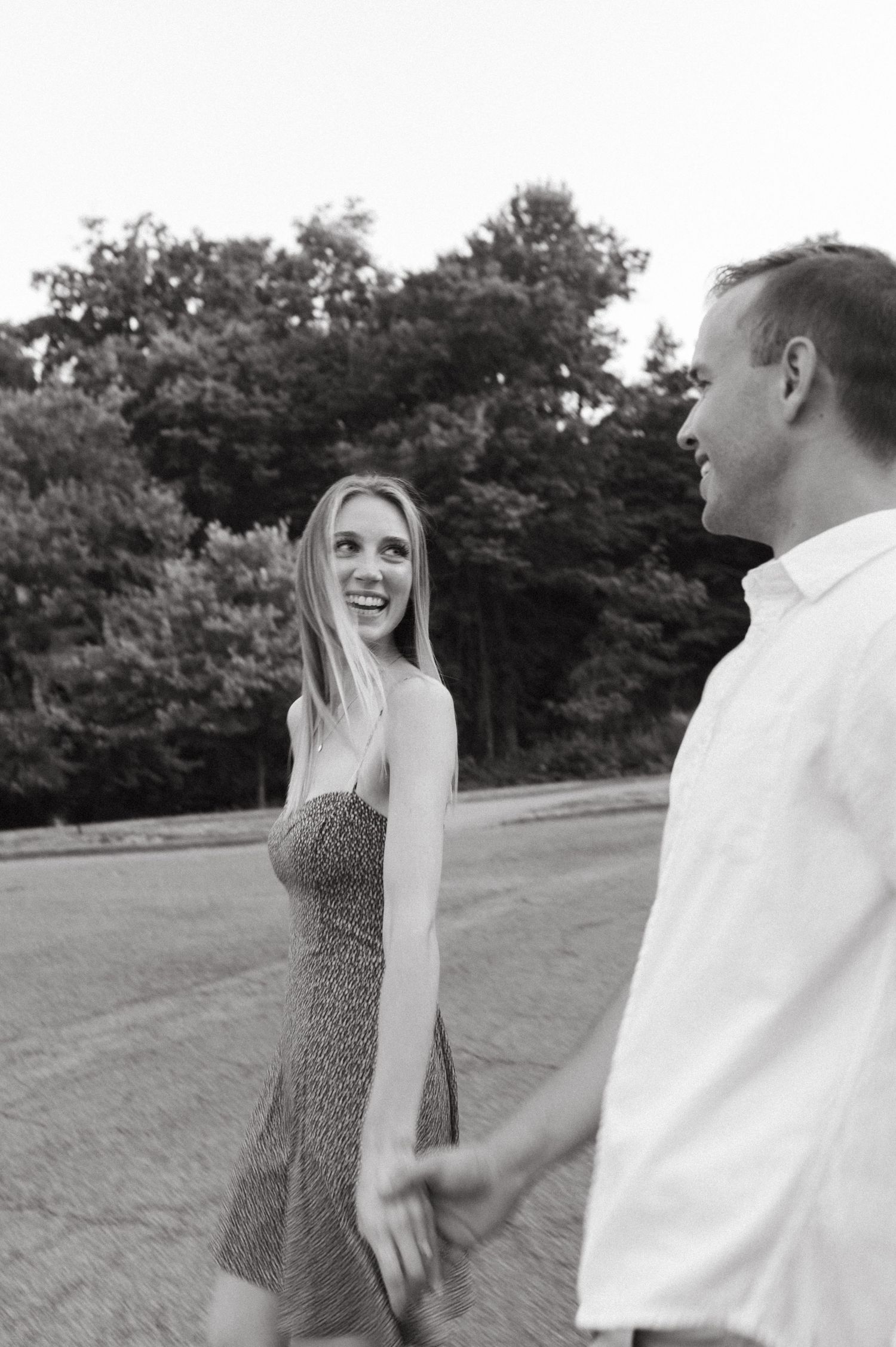 Black and white photo of couple enjoying a lighthearted moment outdoors.