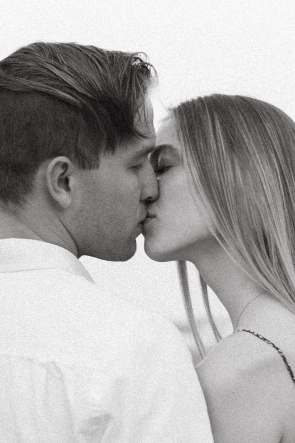 Black and white intimate portrait of a couple sharing a romantic kiss.