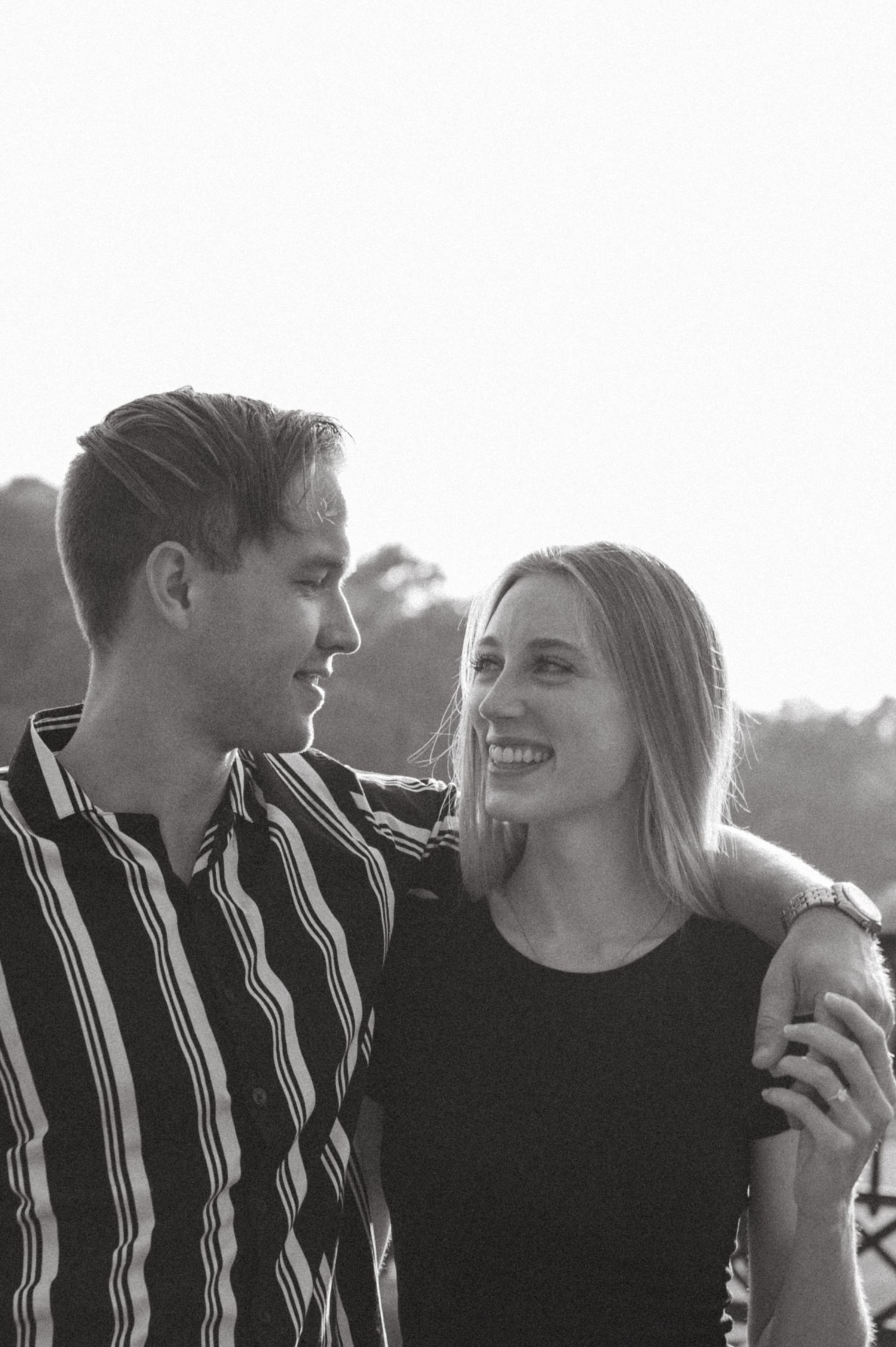 Candid moment of a couple in contrasting outfits sharing a laugh outdoors.