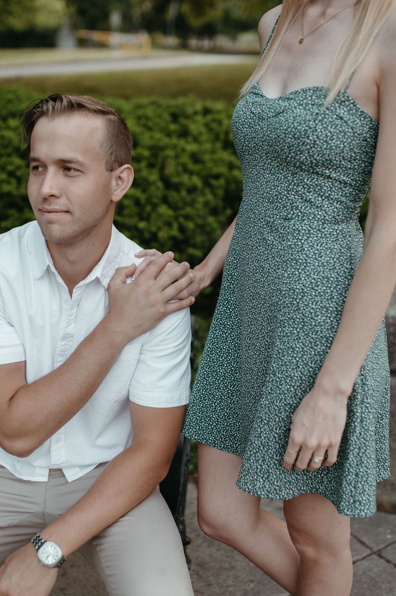Romantic outdoor portrait showing couple in white shirt and green floral dress.